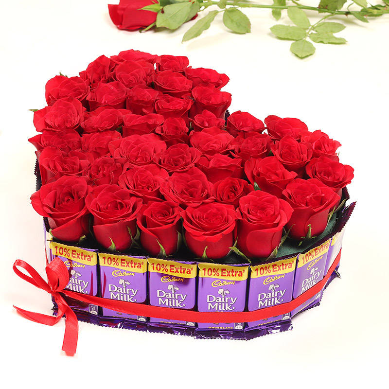 red roses and chocolates in a heart shaped arrangement